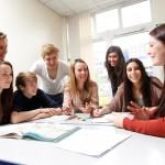 Group of students discussing work together around a desk