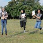 Students jumping for joy holding exam results