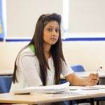 female student at desk holding pen revising