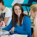 2 female students smiling with male tutor