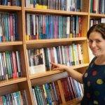 Tutor pointing to book on bookshelf