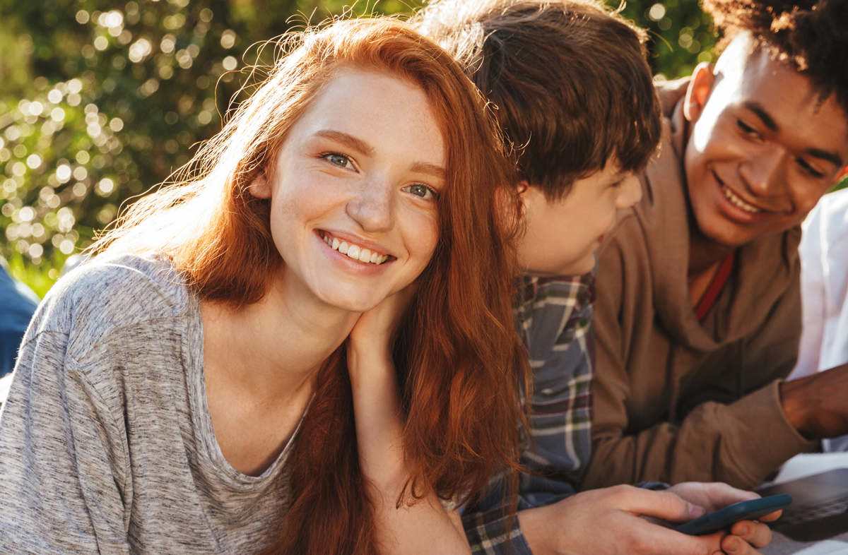 Group of students socialising with a female students smiling at the camera