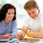 Students studying together, looking at a tablet