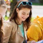 Students sitting outside revising together and smiling